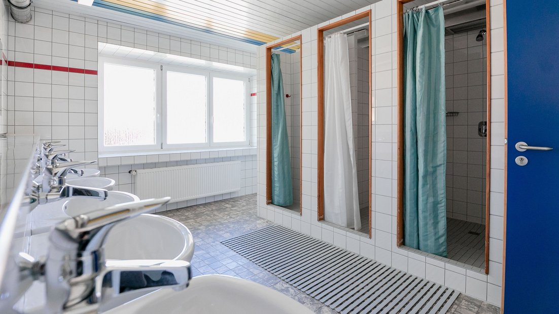 Phòng tắm lát gạch trắng trong ngôi nhà mùa hè với nhiều bồn rửa và vòi hoa sen