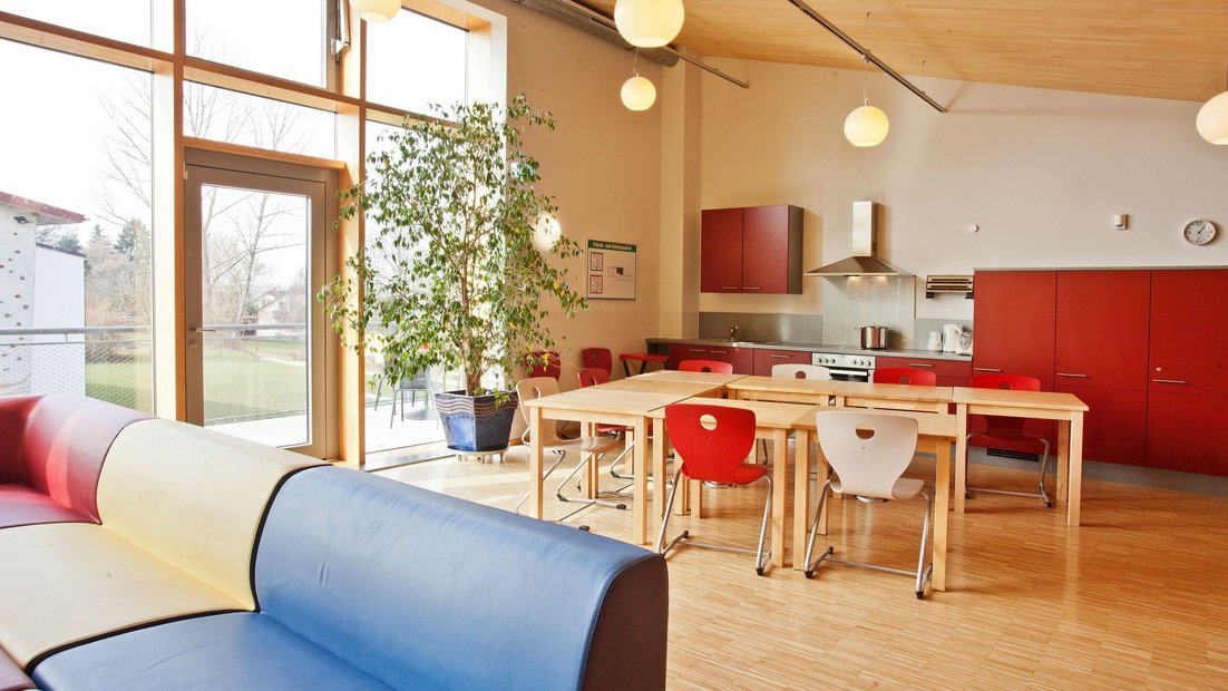Khu vực chung phía trên ở Wiesenhaus với ban công: với bếp nhỏ màu đỏ, nhóm bàn ăn và khu vực ngồi ở phía trước