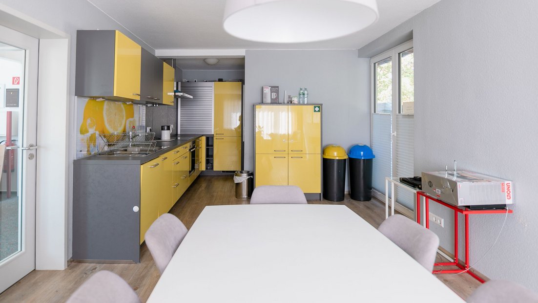 Bếp nhỏ hiện đại màu vàng xám với nhóm bàn ăn ở phía trước